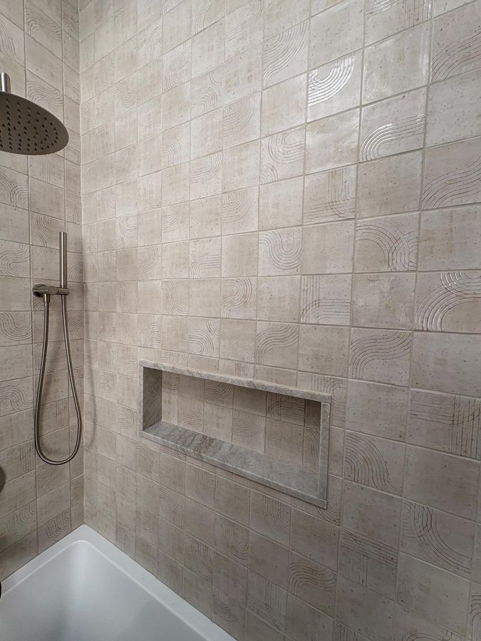 Shower with hand-glazed arched-pattern tile, marble niche and rain shower head